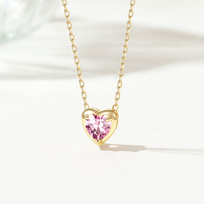 Gold birthstone necklace with a pink heart-shaped gem on a white background
