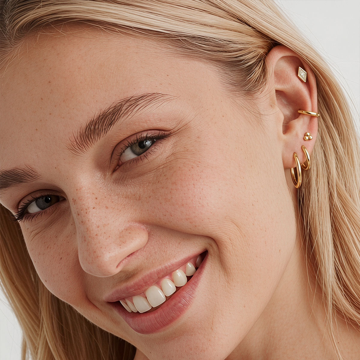 Gold Plated huggie earrings on a light beige surface with a neutral background