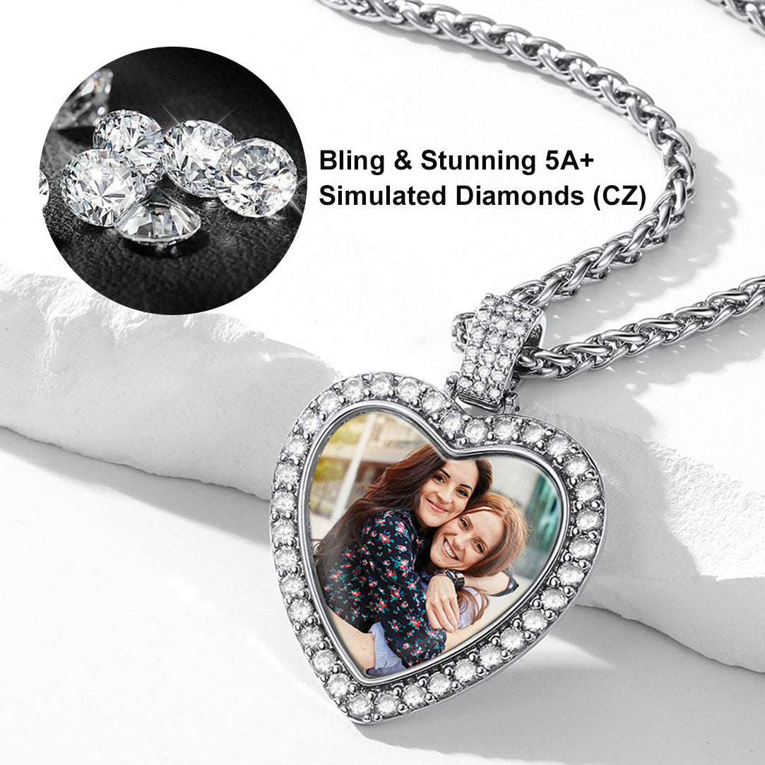 Heart-shaped memorial necklace with photo insert and bling details on a white surface.