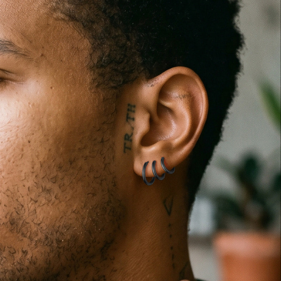 Close-up of a person's ear with tattoos and a blurred background