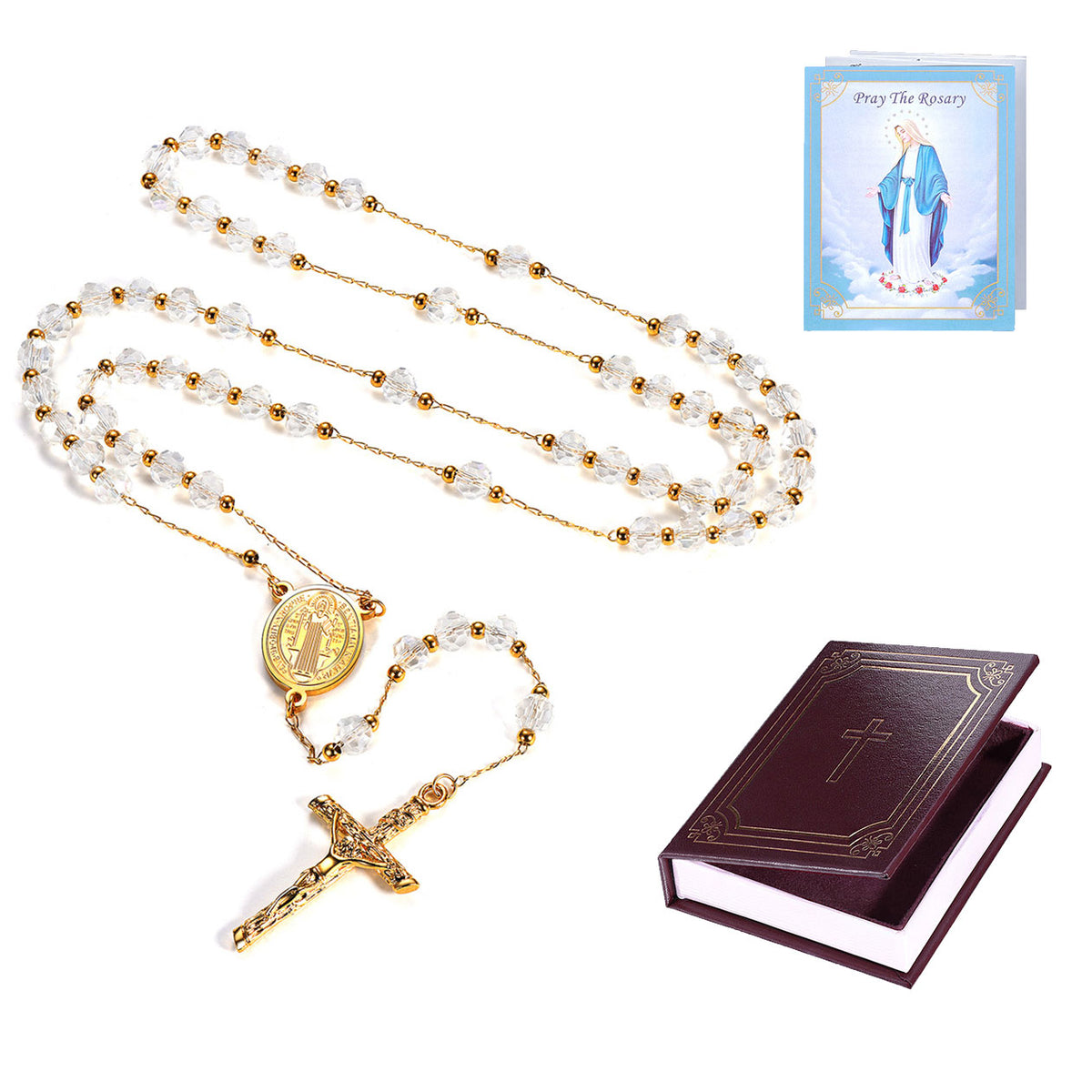 A Catholic rosary with clear crystal beads and a gold-tone crucifix and centerpiece, shown with a small prayer card and a dark brown leather-bound prayer book on a white background.