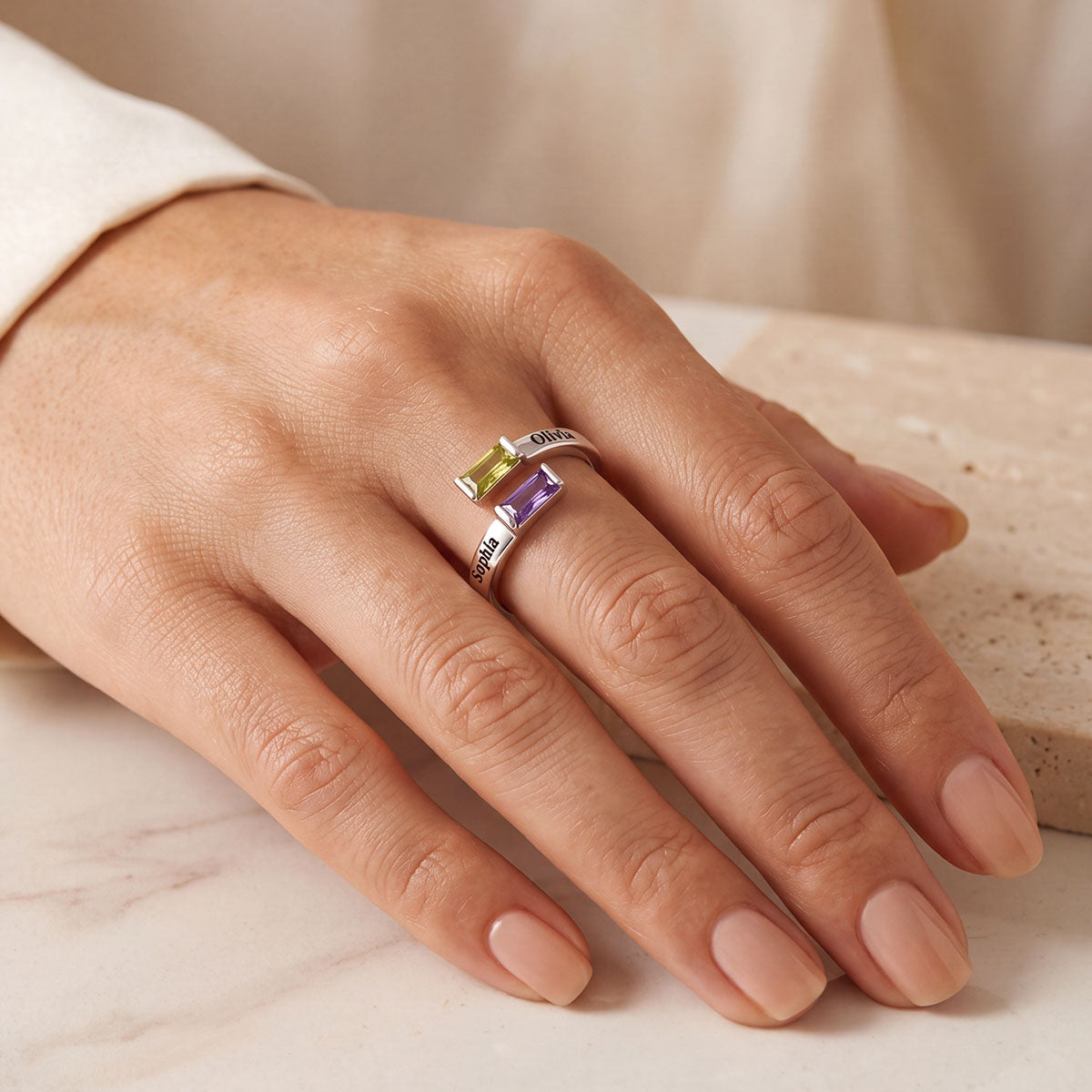 A Hand Wearing Custom Baguette Birthstone Ring for Women Adjustable Ring on a beige background