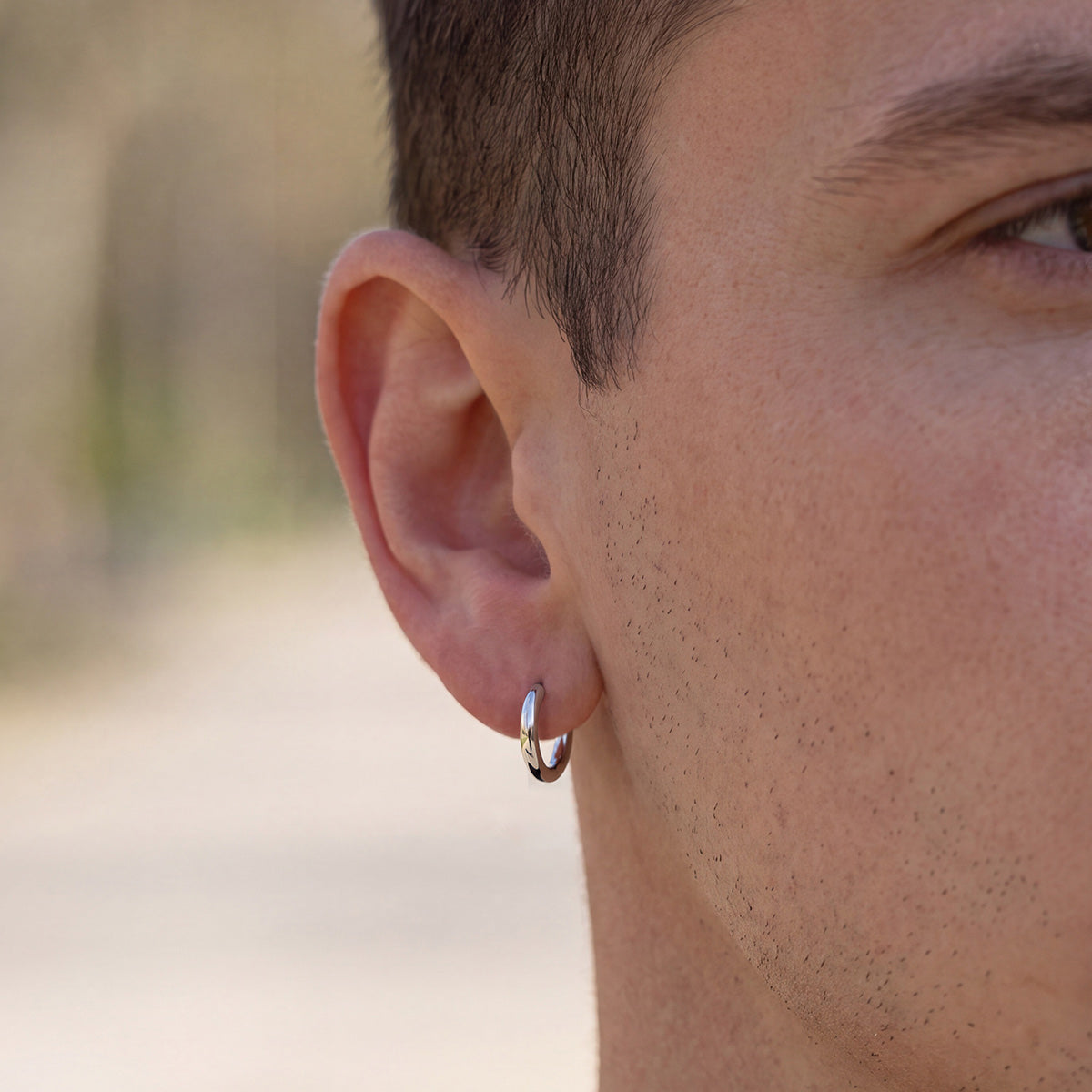 A Man Wearing Classic 18mm Huggie Earrings for Men Women on a white background