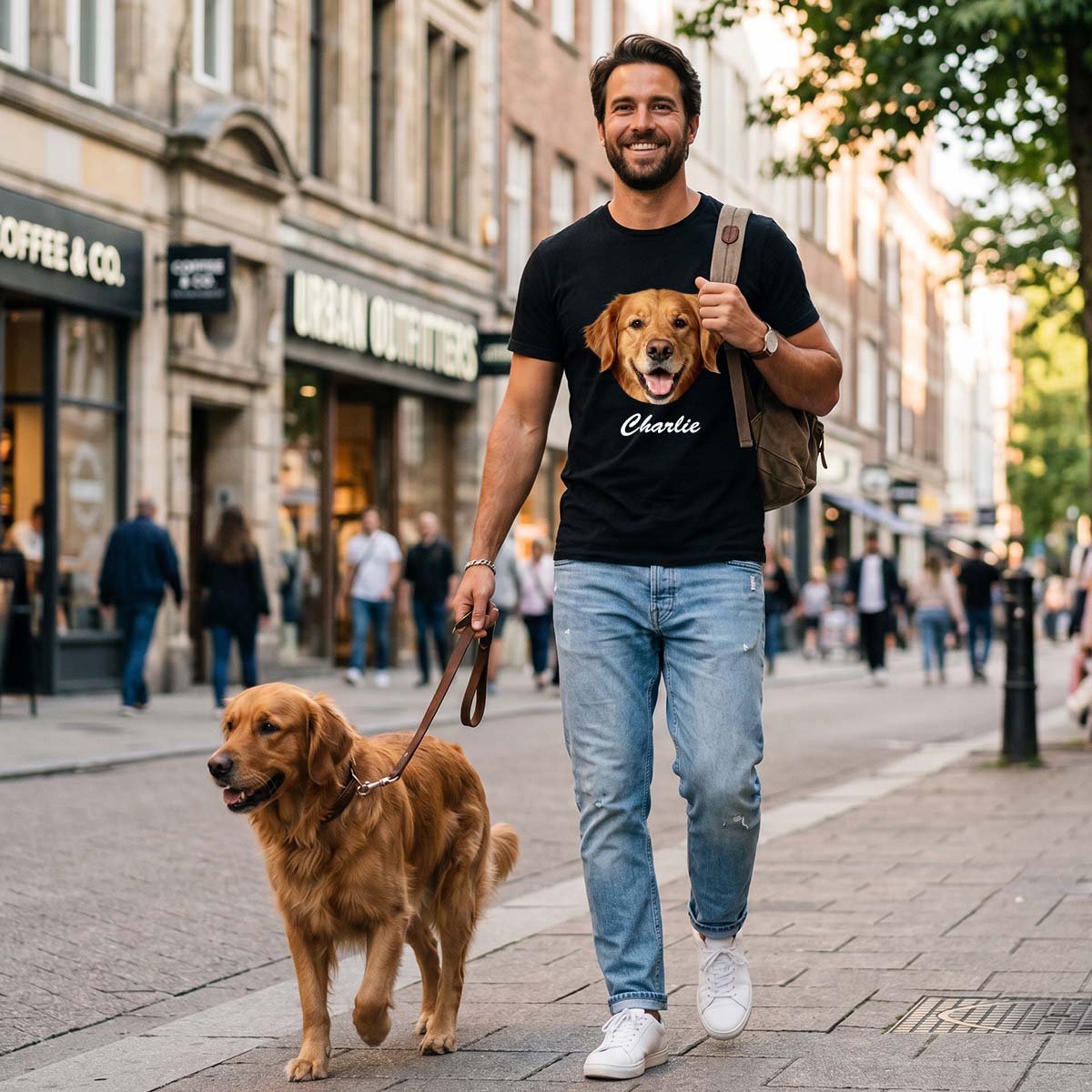 A Man walking a dog on a city street wearing a t-shirt with a dog's face and name.