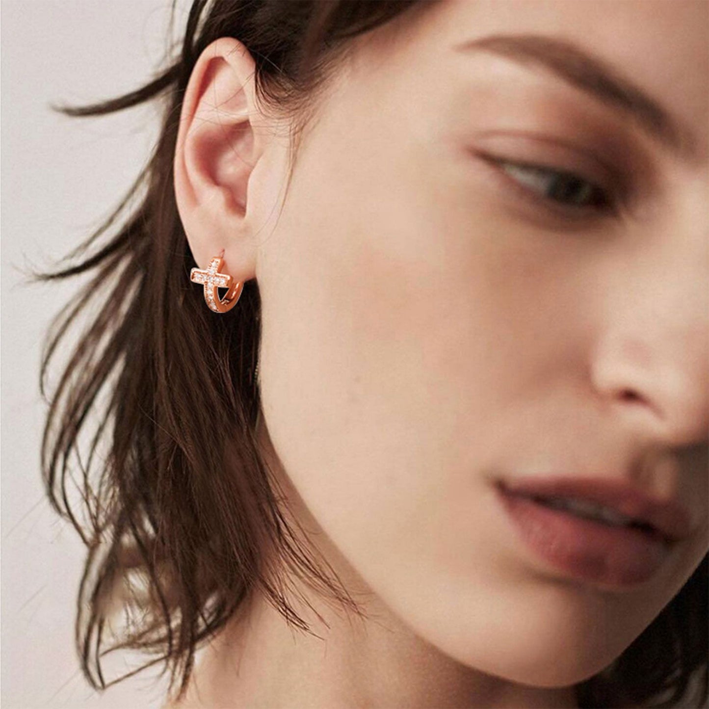 A Woman Wearing Cubic Zirconia Cross Huggie Hoop Earrings