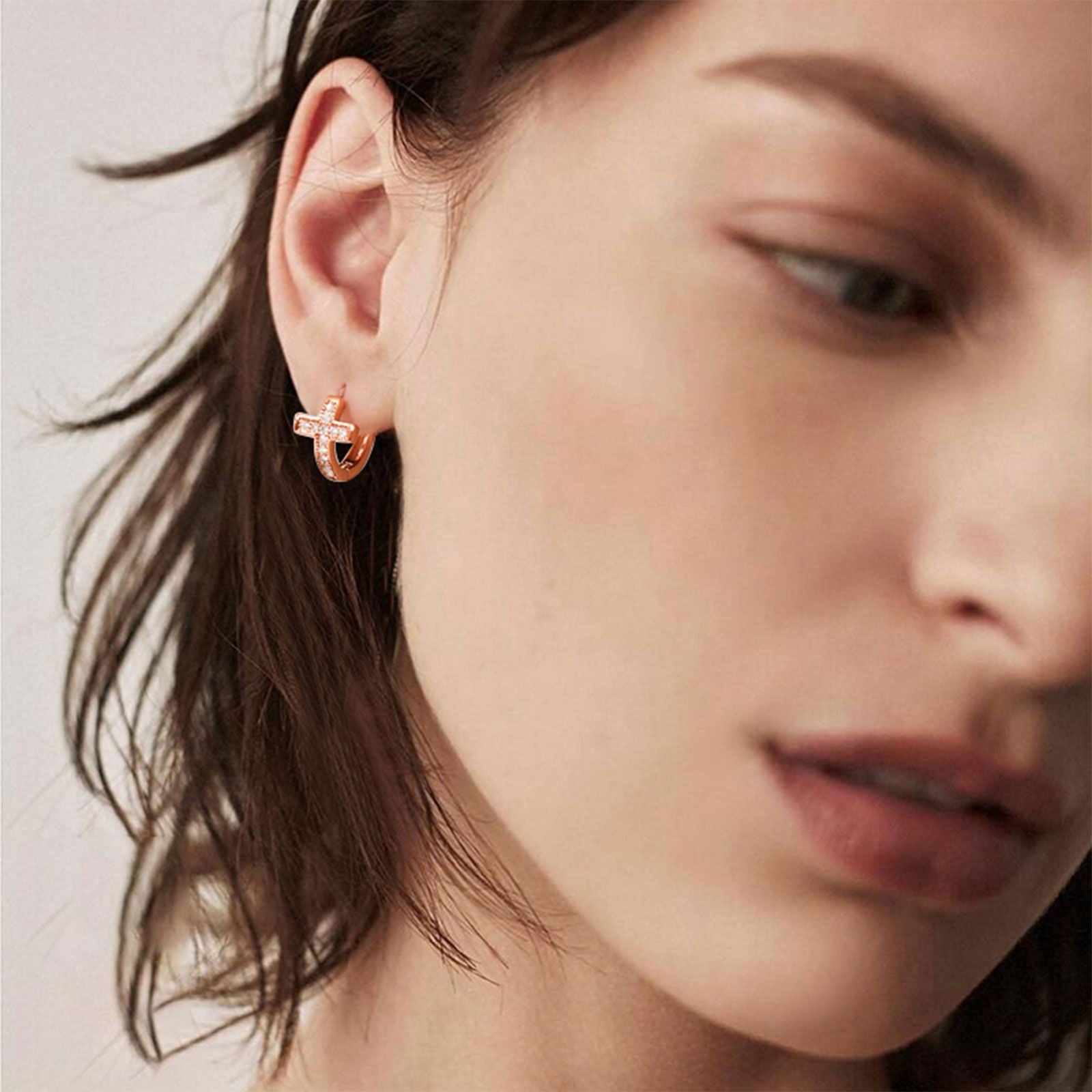 A Woman Wearing Cubic Zirconia Cross Huggie Hoop Earrings