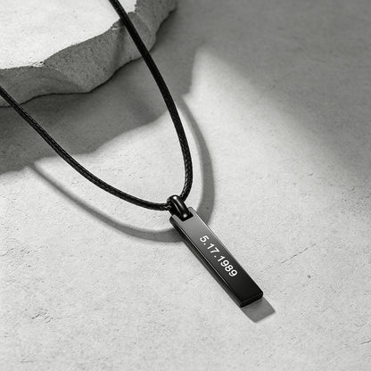 A black metal engraved bar necklace with a rectangular engraved tag reading '5.17.