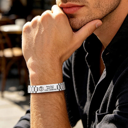 A close-up lifestyle shot of a man wearing a personalized silver medical alert bracelet on his wrist. The bracelet features a bicycle symbol and the engraved text 'David Owen 18.