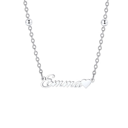 A close-up of a woman wearing a delicate silver name necklace with a small letter 'G' pendant, styled with small silver beads on the chain.