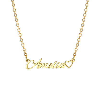 A gold name necklace featuring a script nameplate that reads 'Amelia' in cursive, with a small heart outline at the end, shown on a plain white background.