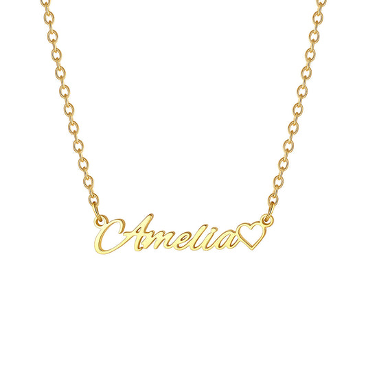 A gold name necklace featuring a script nameplate that reads 'Amelia' in cursive, with a small heart outline at the end, shown on a plain white background.