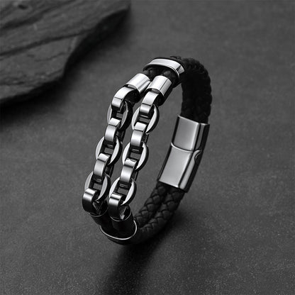A men's double-strand bracelet featuring a black braided leather strap and a polished silver-tone stainless steel chain link design, displayed on a dark textured surface.