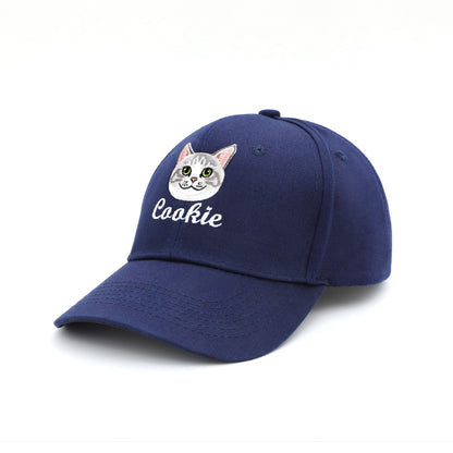A navy blue pet baseball cap featuring an embroidered cat face and the name 'Cookie' in white script on the front, shown against a plain white background.