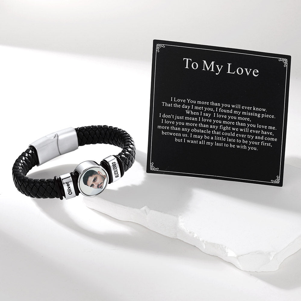 A personalized black braided cord photo bracelet with silver-toned metal accents and a circular photo charm, displayed next to a black printed card that reads 'To My Love' with a poem. The photo charm shows a man's face with the name 'James' on the side.