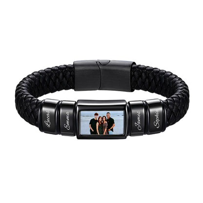 A personalized black braided leather and metal bracelet featuring a central rectangular photo frame and four engraved name beads, shown on a plain white background.