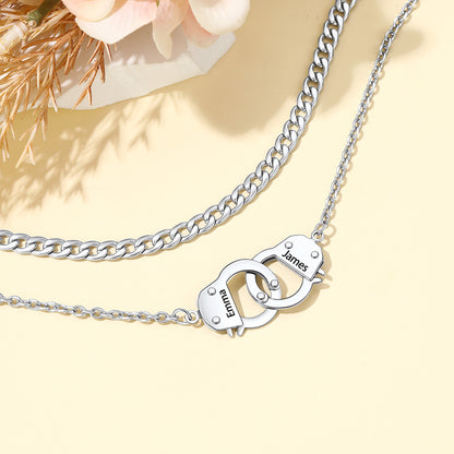 A silver-toned double-layer hankcuff anklet on a light yellow background