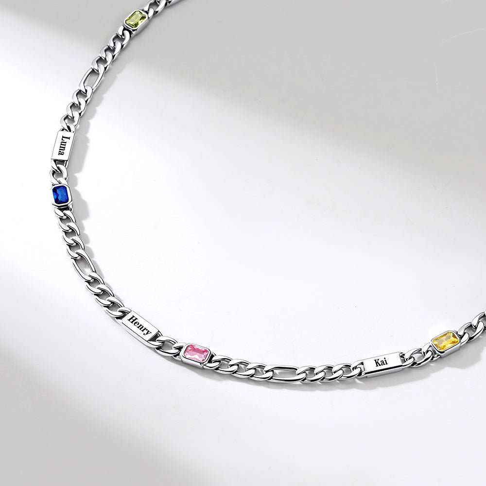 A silver Cuban link chain necklace with custom engraved name plates and small colorful gemstone accents in blue, pink, yellow, and green, displayed on a clean white background.