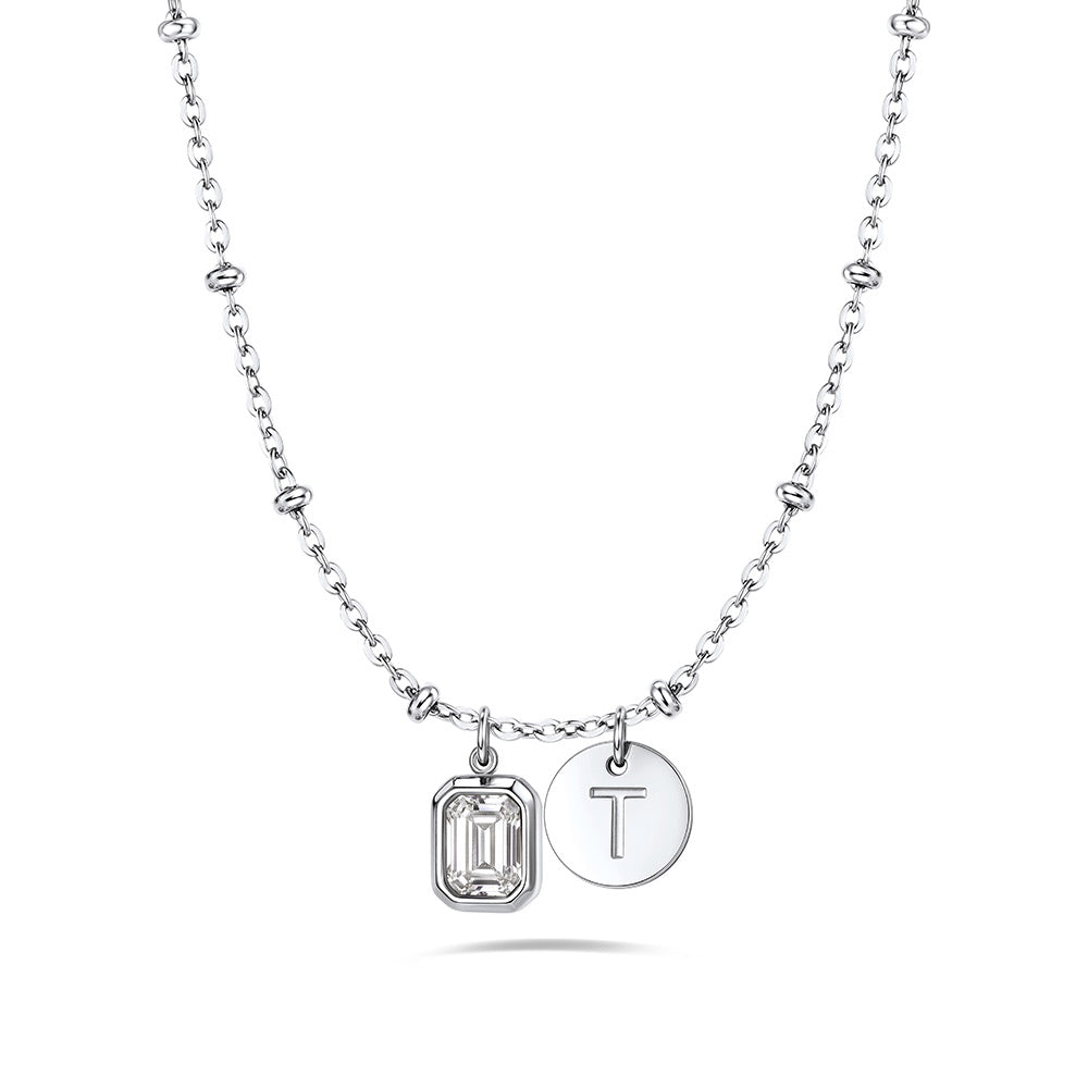 A silver birthstone initial necklace featuring a beaded chain, a rectangular bezel-set clear gemstone charm, and a round engraved silver disc charm with the letter 'T', shown on a clean white background.