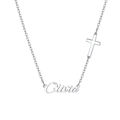 A silver chain name necklace featuring a small cross pendant and a script nameplate reading 'Olivia', shown on a plain white background.