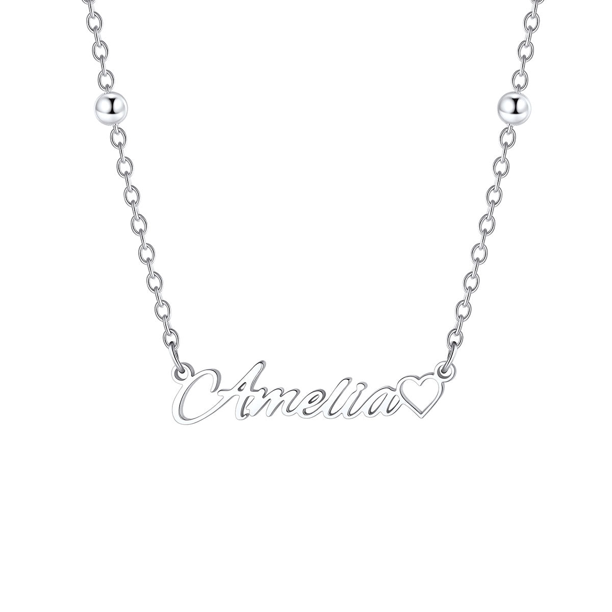 A silver name necklace featuring a script nameplate that reads 'Amelia' in cursive, with a small heart outline at the end of the word, shown on a plain white background.