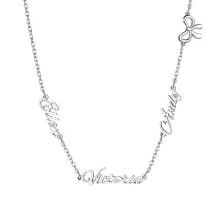 A silver name necklace featuring the names 'Elowen', 'Clary', and 'Victoria' in cursive script, with a small bow charm at the top, shown on a plain white background.