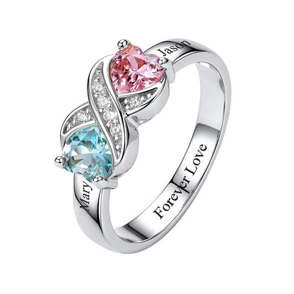 A sterling silver infinity birthstone ring featuring a pink heart-shaped gemstone and a light blue heart-shaped gemstone, accented with small clear stones. The band is engraved with the names 'Mary' and 'Jason' and the phrase 'Forever Love'.