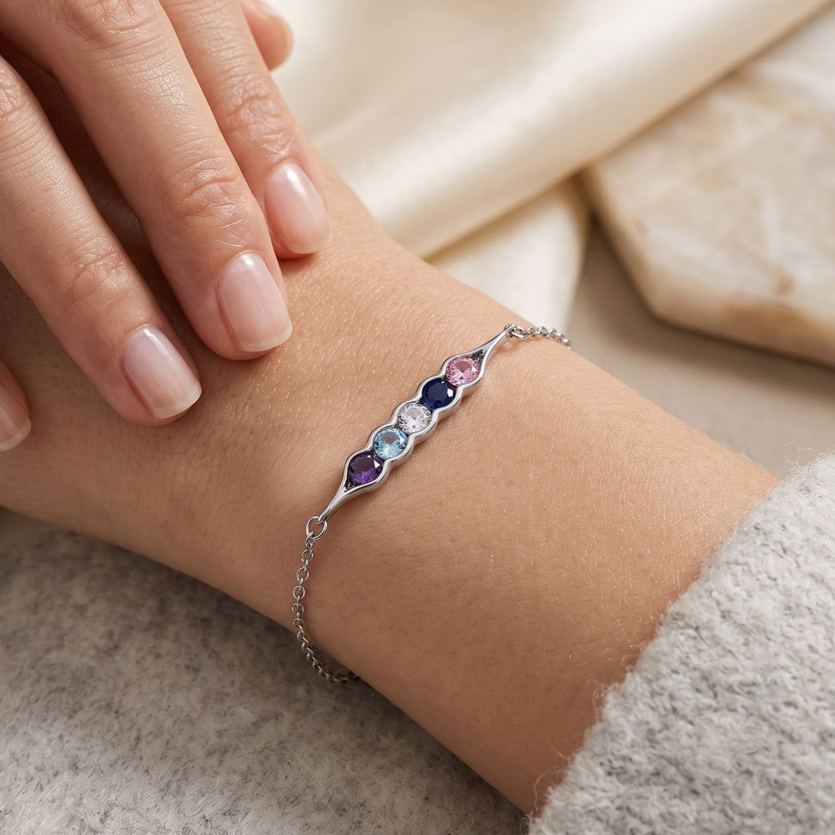 Birthstone Bracelet with colorful gemstones on a wrist against a neutral background