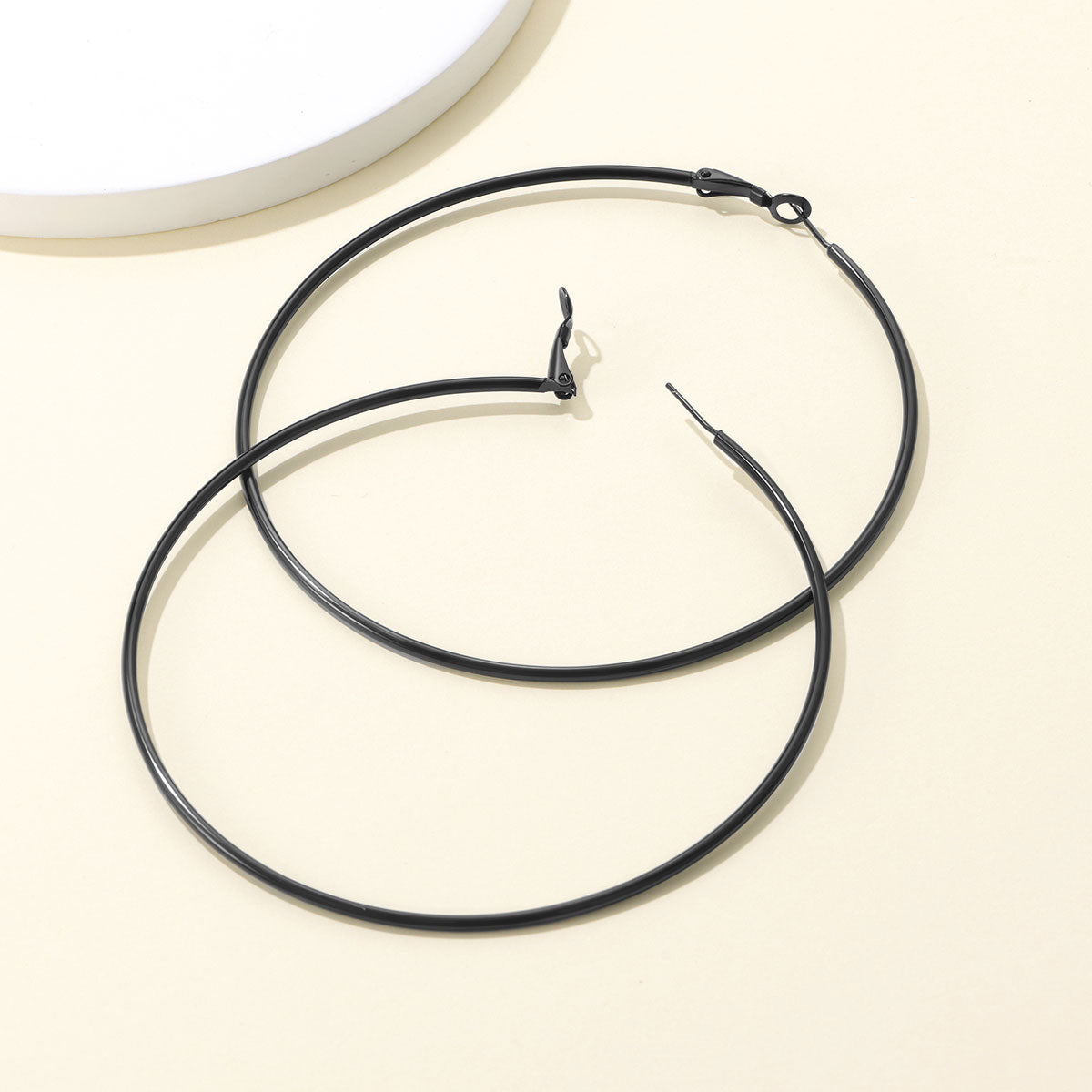 Black Classic Statement Hoop Earrings for Women on a ligth yellow background
