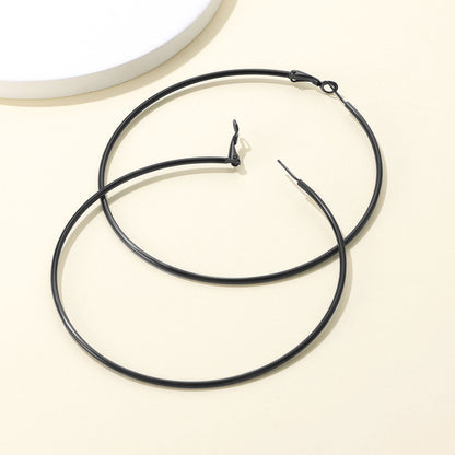 Black Classic Statement Hoop Earrings for Women on a ligth yellow background