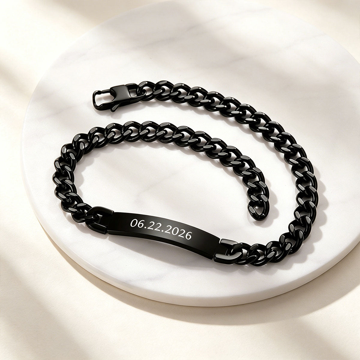 Black Cuban chain necklace with engraved date on a white surface