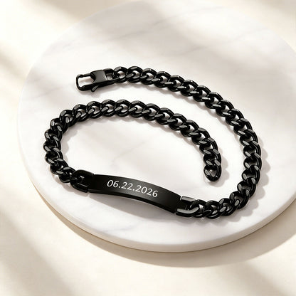 Black Cuban chain necklace with engraved date on a white surface