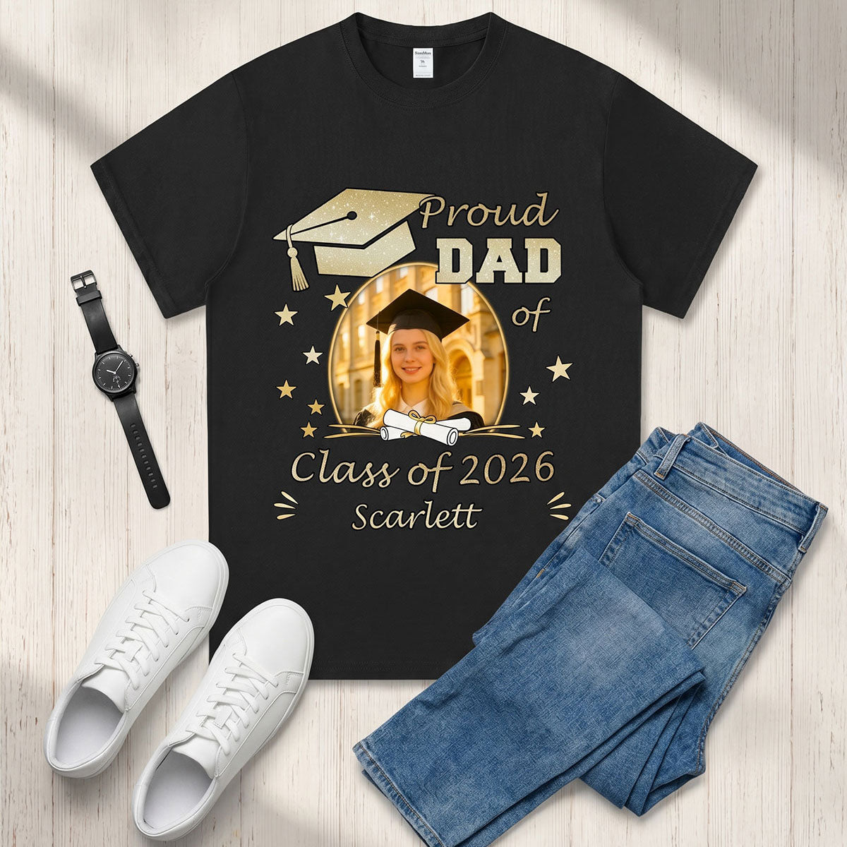 Black custom photo graduation t-shirt with 'Proud Dad of Class of 2026 Scarlett' design, paired with white sneakers and blue jeans on a wooden surface.