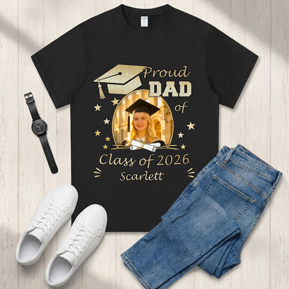 Black custom photo graduation t-shirt with 'Proud Dad of Class of 2026 Scarlett' design, paired with white sneakers and blue jeans on a wooden surface.