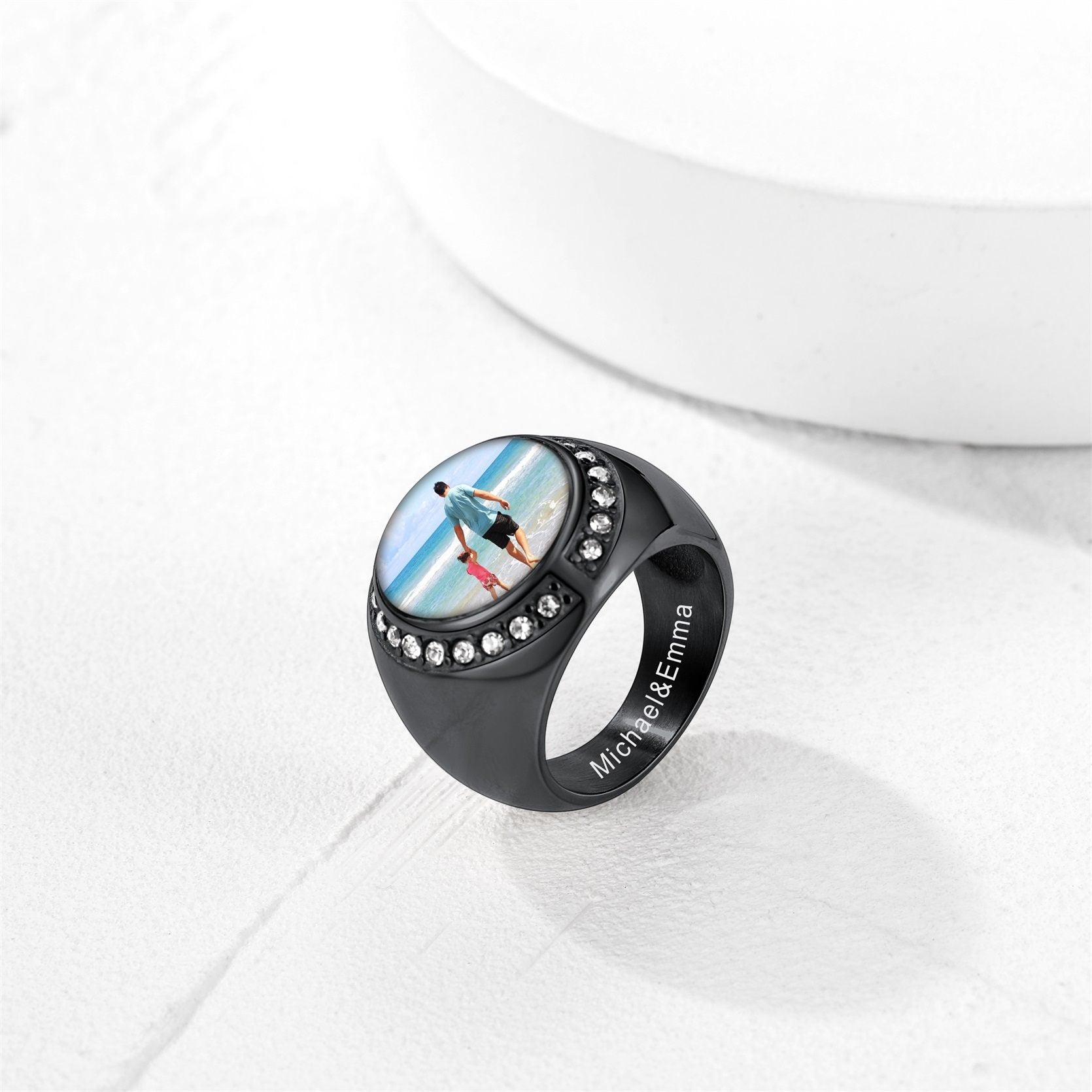 Black picture signet ring with a circular design featuring a person on a beach, set against a white background.