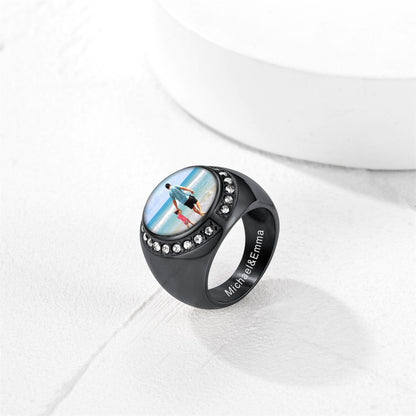 Black picture signet ring with a circular design featuring a person on a beach, set against a white background.