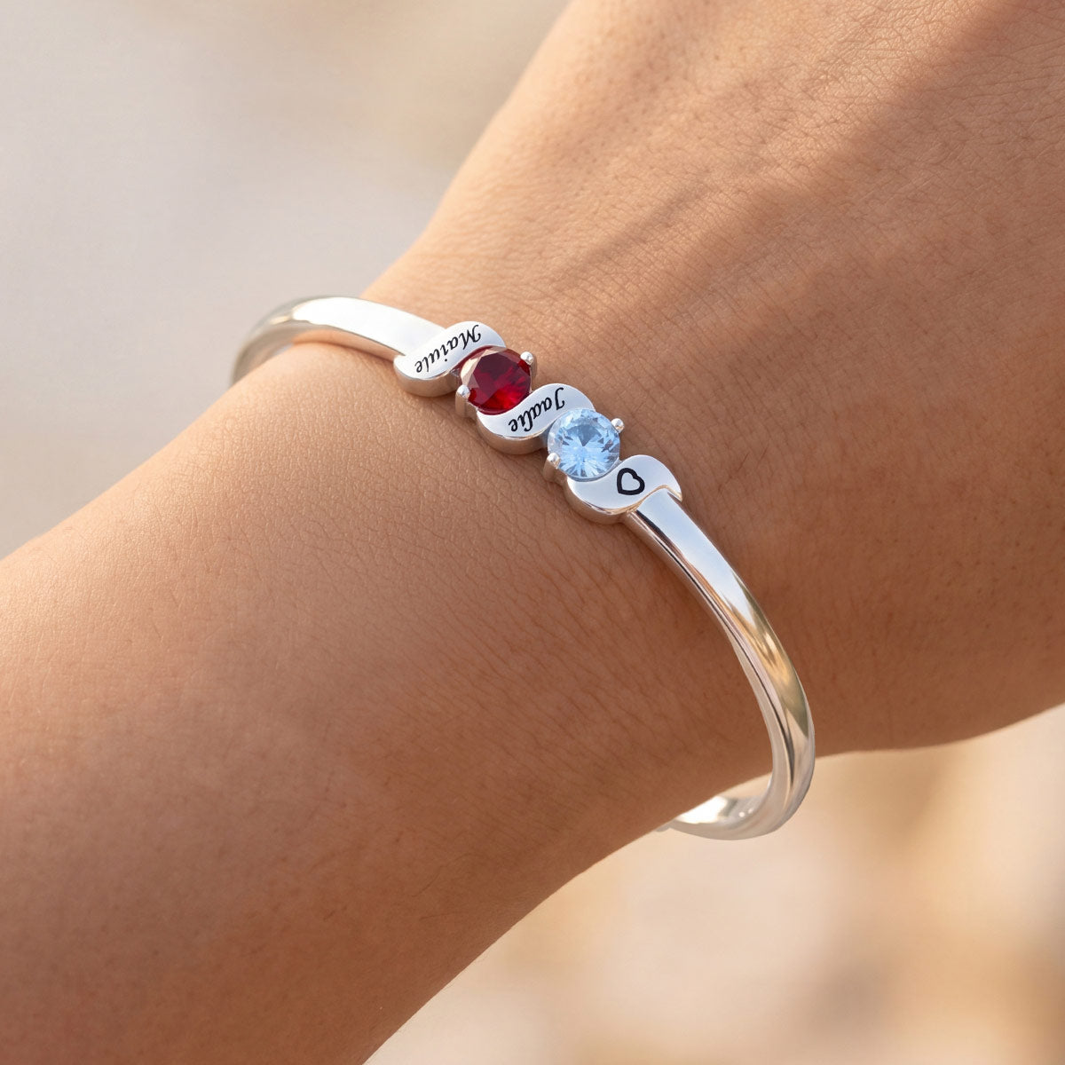 Silver bracelet with gemstones on a wrist against a neutral background