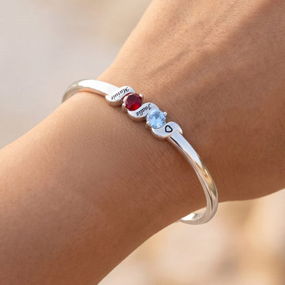 Silver bracelet with gemstones on a wrist against a neutral background
