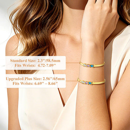 Gold birthstone bracelets on a person's wrist with size information displayed.