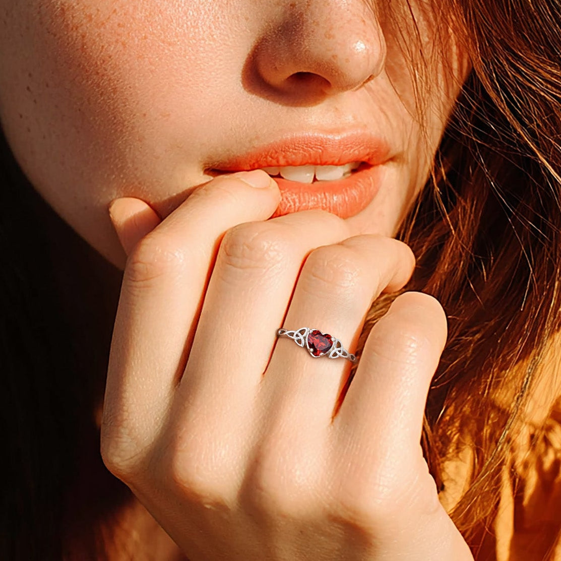 Close-up of a woman with freckles and a ring on her finger, wearing an orange top.