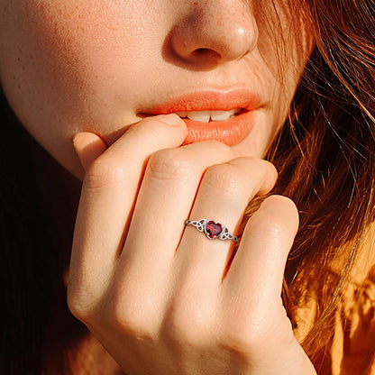 Close-up of a woman with freckles and a ring on her finger, wearing an orange top.
