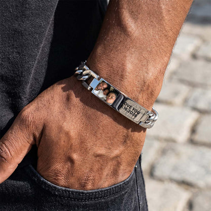 Close-up of a person's wrist wearing a silver chain picutre bracelet with engraved details.