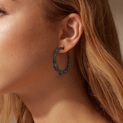 Close-up of a person wearing a bamboo hoop earring with blonde hair.