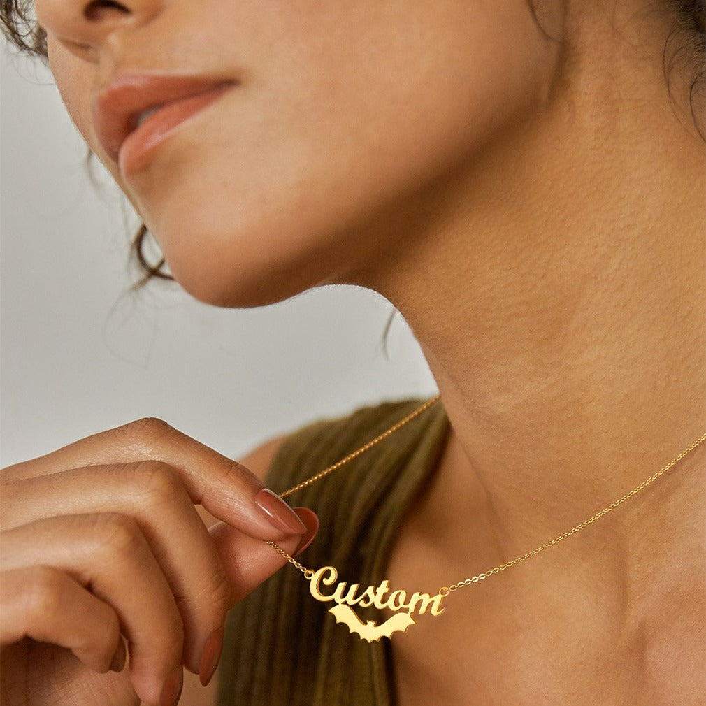 Close-up of a person wearing a gold 'Custom' name necklace against a neutral background