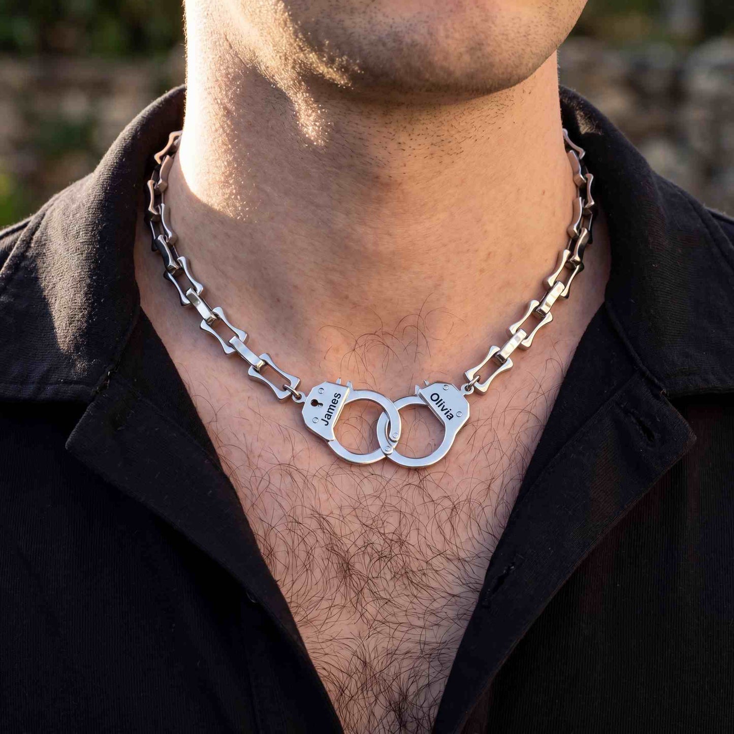Close-up of a person wearing a silver handcuff chain necklace 