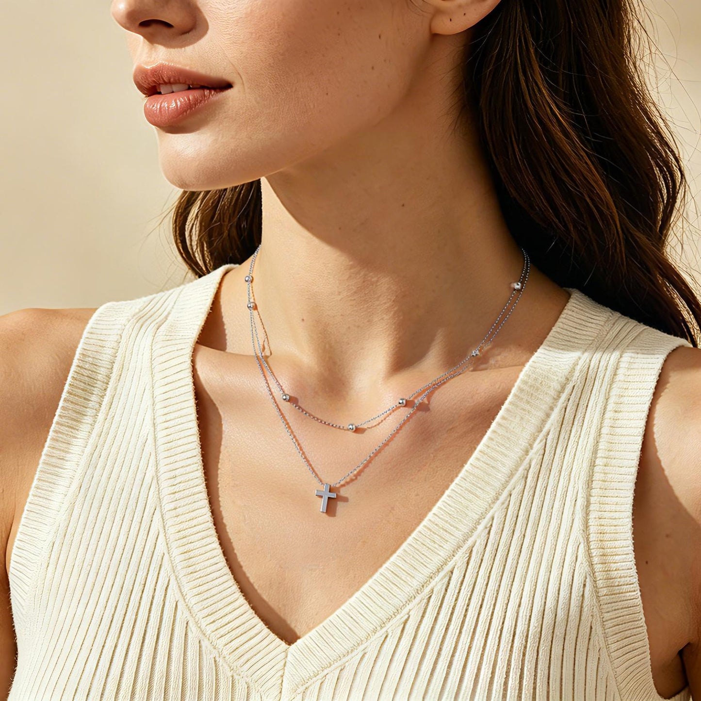 Close-up of a woman wearing a delicate necklace with a cross pendant.
