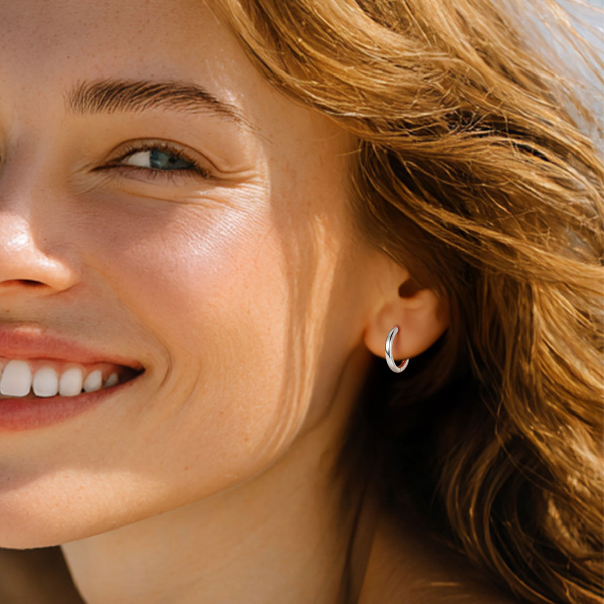 Close-up of a woman wearing a silver hoop earring with a blurred background