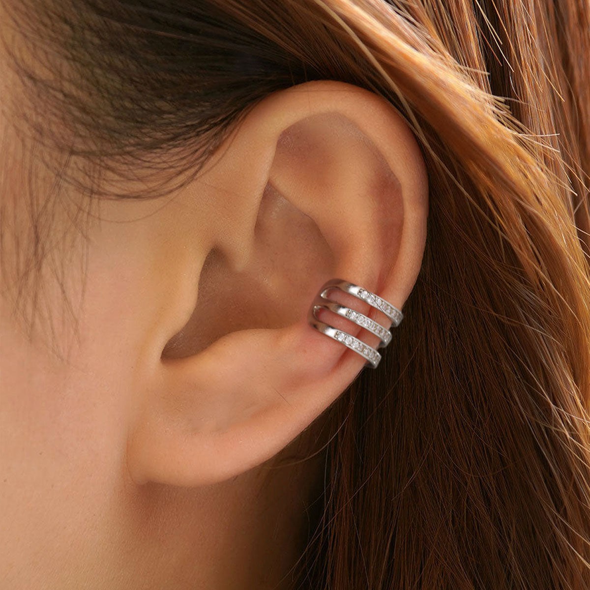 Close-up of an ear wearing a silver cz earring with hair partially obscuring the view.