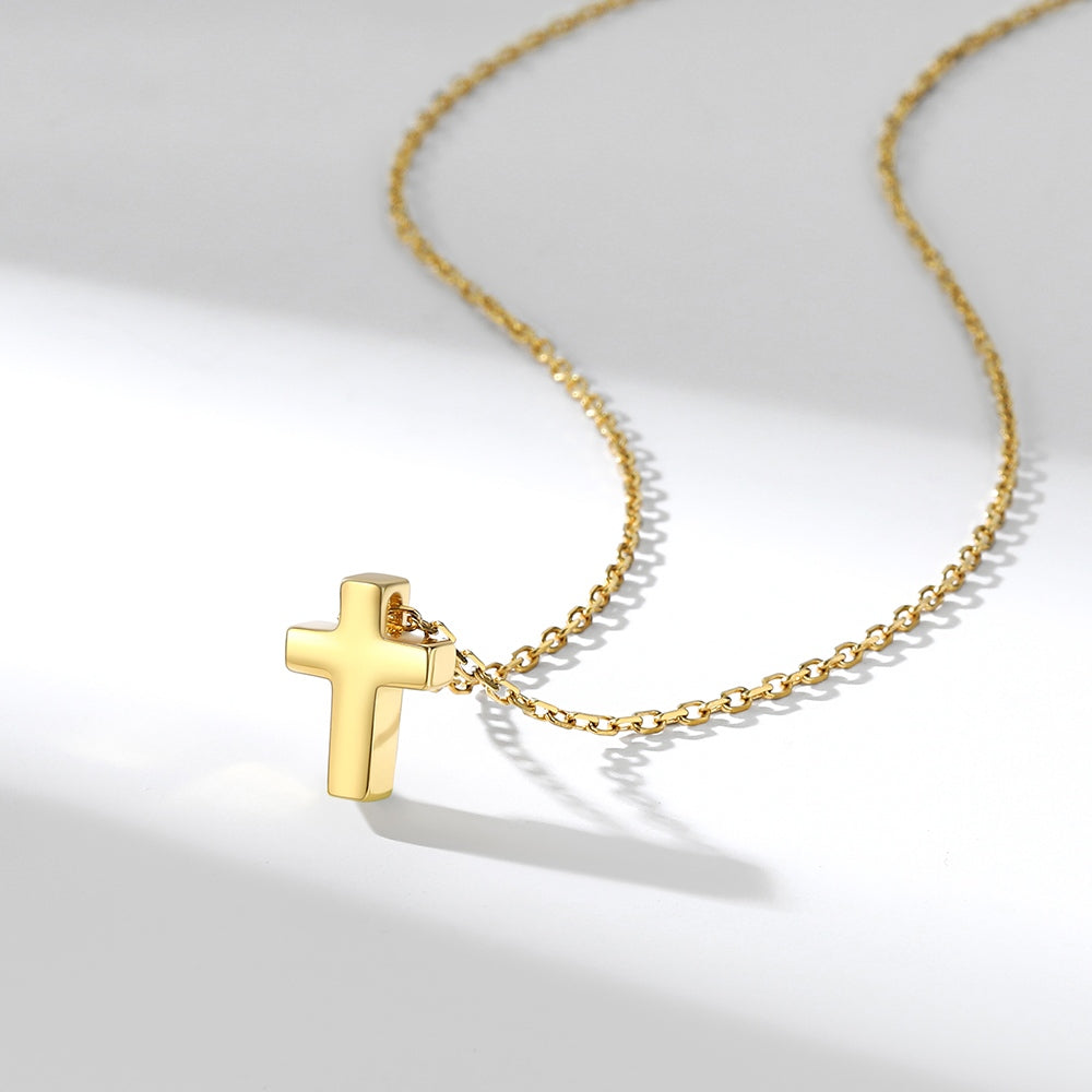 Gold cross necklace on a light gray background
