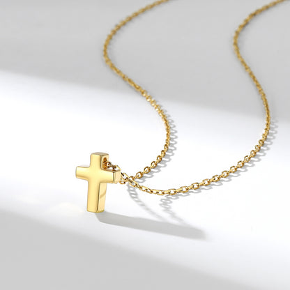 Gold cross necklace on a light gray background