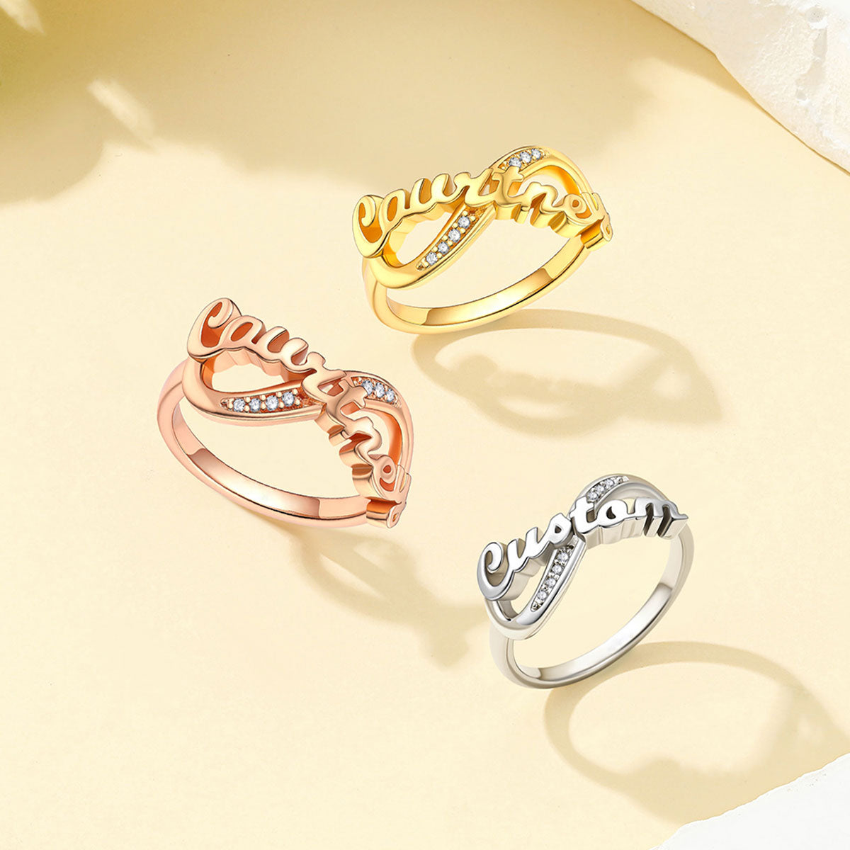 Custom Name Infinity Promise Ring With Cubic Zirconia in different color on a light yellow background
